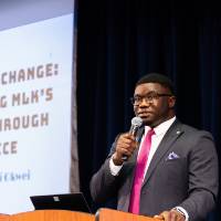 Albert&nbsp;Okwei with microphone at podium
